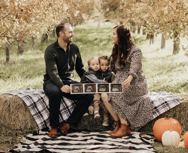 Photo of family holding ultrasound pictures as part of a pregnancy announcement.