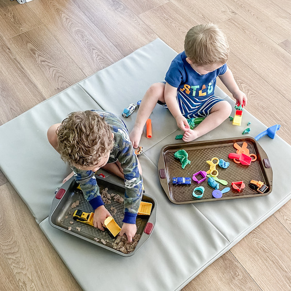 Boys sitting playing with kinetic sand and play doh