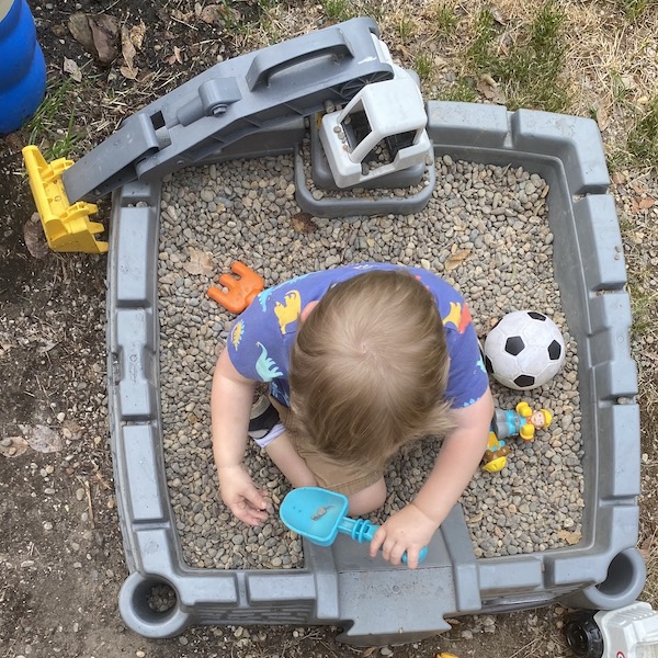 Boy sitting in rock box playing with diggers.