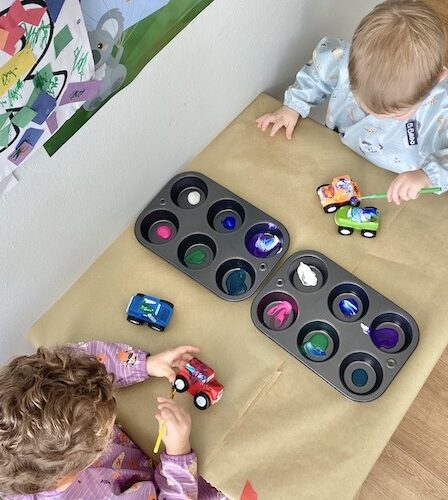 Toddlers playing with paint and cars