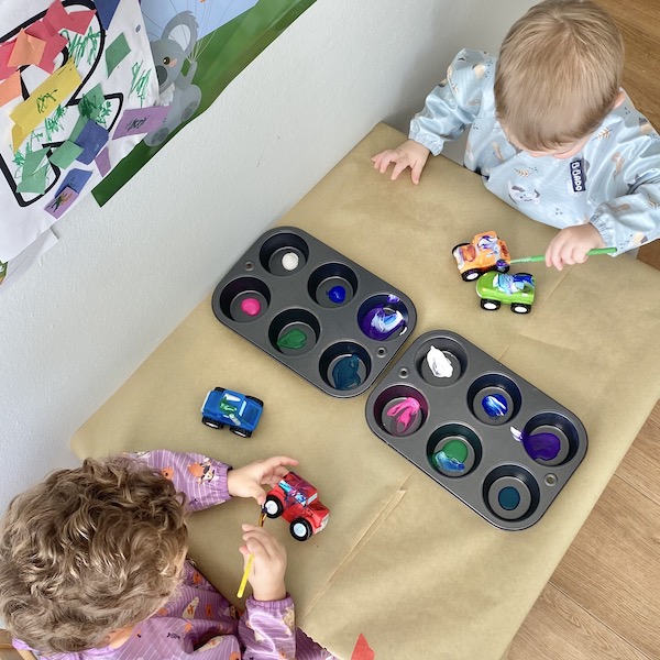 Boys painting toy cars with washable paint.