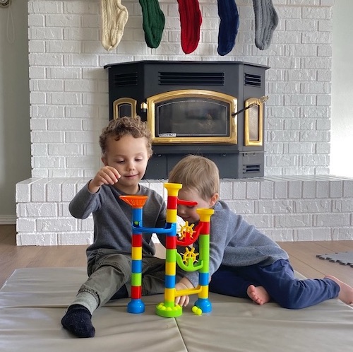 Boys sitting on floor playing with marble run learning puzzle toy