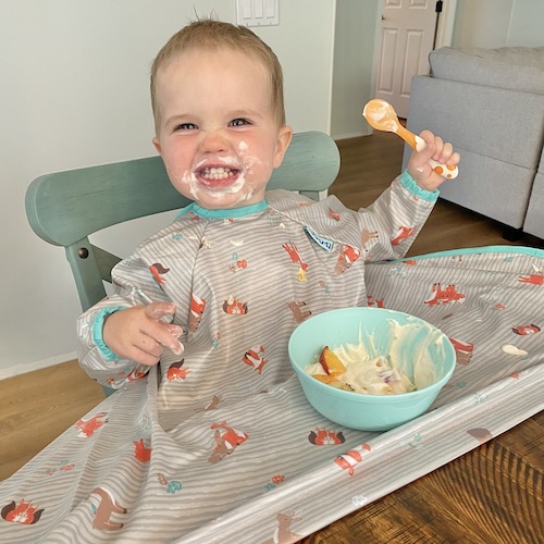 Boy eating yogurt at table.