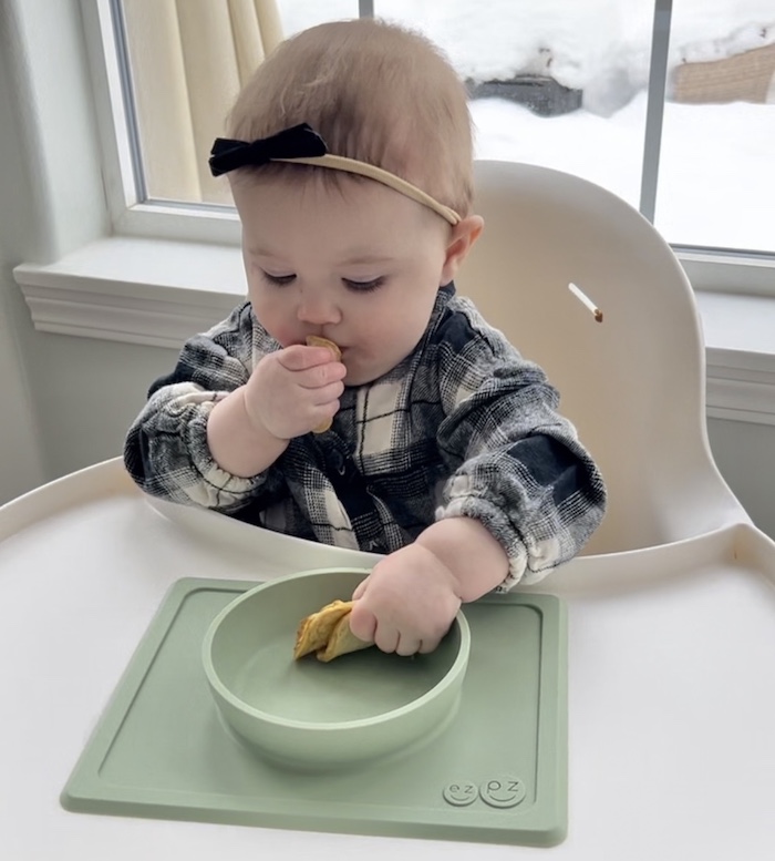 Baby self-feeding food in high chair