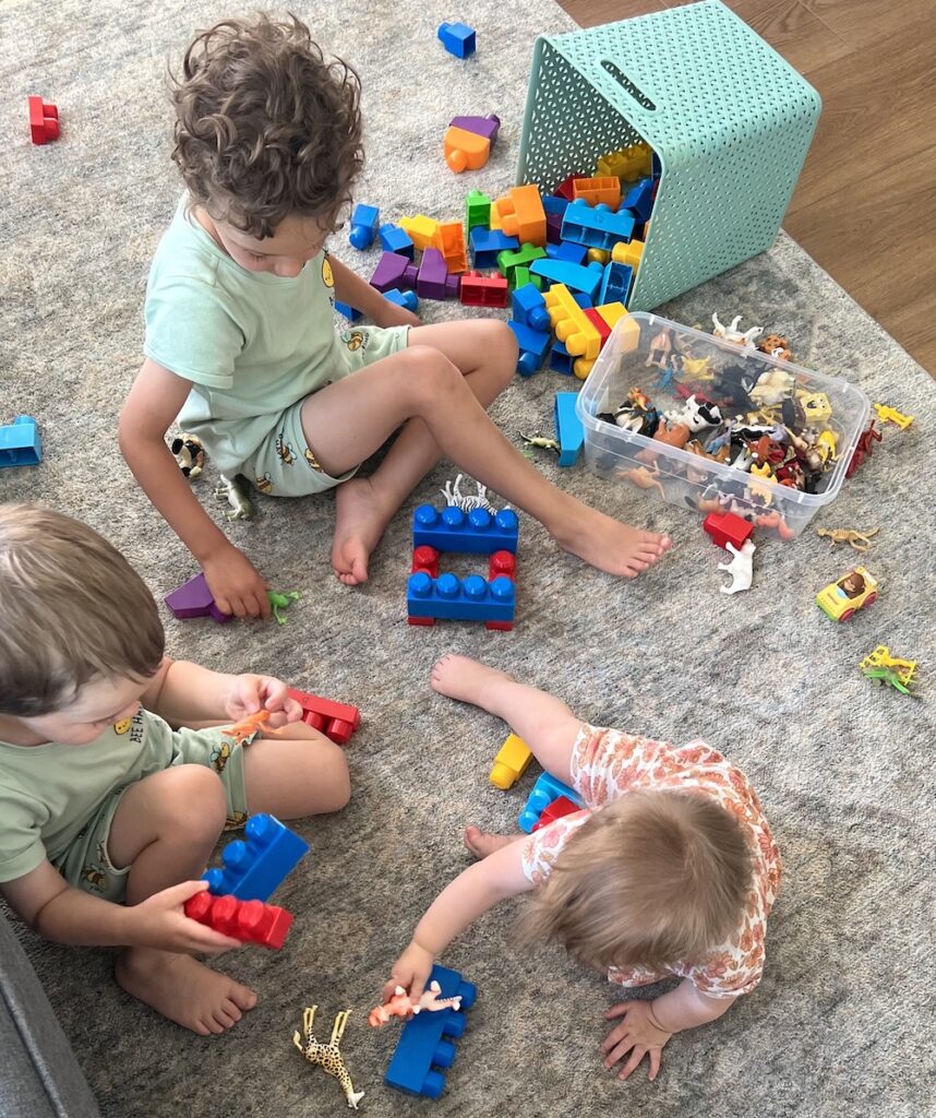 Toddlers playing with blocks and animal figurines (learning toys)
